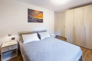 a white bedroom with a bed and a cabinet at La Sorgente Ville di Fiemme in Carano