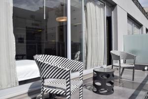 Hotel BA Abasto في بوينس آيرس: كرسيين وطاولة على شرفة مع سرير