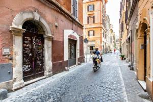 una persona che va in bicicletta lungo una strada di ciottoli di Pop House a Roma