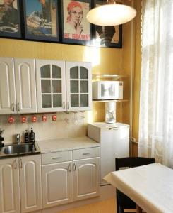 eine Küche mit weißen Schränken, einer Spüle und einer Mikrowelle in der Unterkunft Retro Apartment in Kiviõli in Kiviõli