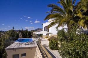 a villa with a swimming pool and a palm tree at Villa Quimera - Plusholidays in Benissa