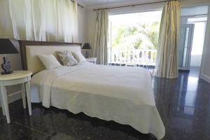 a bedroom with a white bed and a balcony at Chateau Elysium - Two bedroom villa 2 in Beau Vallon
