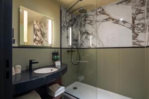 a bathroom with a sink and a shower at voco Paris - Porte de Clichy, an IHG Hotel in Clichy