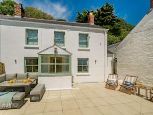 a white house with a patio with a table and chairs at 3 Bed in Portloe 87260 in Portloe