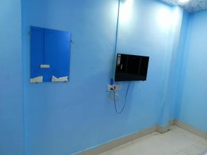 a room with a blue wall with a tv at M Baba Guest House in Ujjain