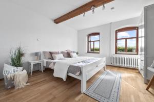 a white bedroom with a bed and two windows at Ferienwohnung Hohe Luft EG in Steinberg