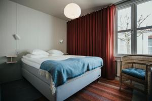1 dormitorio con 1 cama con manta azul y ventana en Gullmarsstrand Hotell & Konferens, en Fiskebäckskil