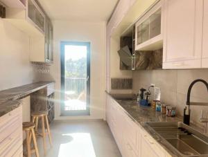 eine Küche mit weißen Schränken, einem Waschbecken und einem Fenster in der Unterkunft Golden beryl - Selestate in Braşov