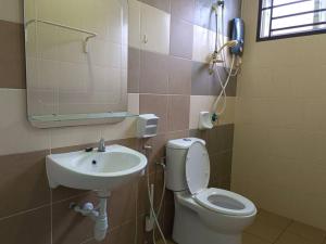 a bathroom with a sink and a toilet and a mirror at Homestay Desaru Utama @Escadia in Bandar Penawar