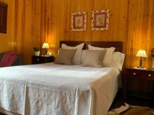 1 dormitorio con 1 cama blanca y paredes de madera en El Xalet de Taüll Hotel Rural en Taull