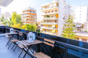 a row of chairs and tables on a balcony with buildings at Gtrip P Faliro Coastal Comfort 2F in Athens