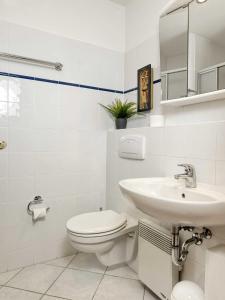 a white bathroom with a toilet and a sink at Ferienwohnungen Fischerstieg Pier 17 in Timmendorf