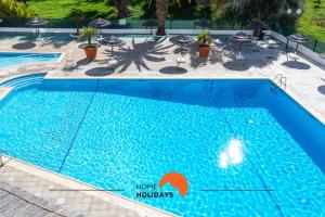a large blue swimming pool with chairs and umbrellas at #048 Sea and City view with Pool, AC in Brejos