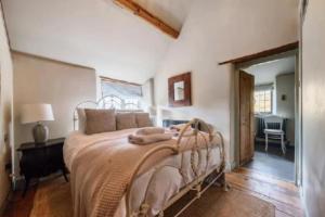 a bedroom with a large bed in a room at 18th Cent Cottage - 5min drive Soho Farmhouse in Ledwell