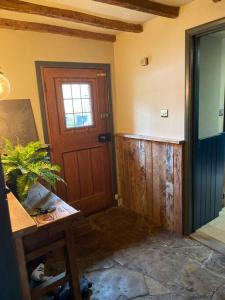 a room with a door and a table with a plant at 18th Cent Cottage - 5min drive Soho Farmhouse in Ledwell