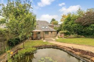 an exterior view of a house with a pond at 18th Cent Cottage - 5min drive Soho Farmhouse in Ledwell