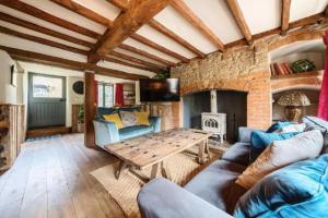 a living room with a couch and a table at 18th Cent Cottage - 5min drive Soho Farmhouse in Ledwell