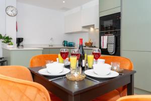 a black table with glasses of red wine and orange chairs at Watford Cassio Supreme - Modernview Serviced Accommodation in Watford