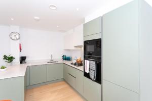 a kitchen with white cabinets and a black appliance at Watford Cassio Supreme - Modernview Serviced Accommodation in Watford