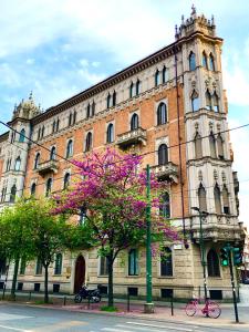 un grande edificio in mattoni con un albero fiorito di fronte di Suite Sommeiller Comfort in centro a Torino