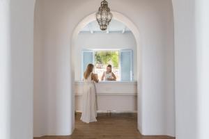 une femme en robe blanche debout devant un miroir dans l'établissement Calme Boutique Hotel - Adults Only, à Drios