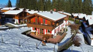 een groot houten huis met rode deuren in de sneeuw bij Feriendorf Via Claudia Haus 59 Gamsbock in Lechbruck