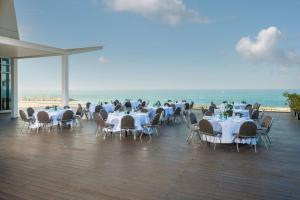 テルアビブにあるヒルトン テル アビブ ホテルの海とテーブルと椅子が備わるレストラン