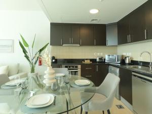 a kitchen with a glass table and white chairs at HiGuests - Duplex Haven in Laguna Tower with City Views in Dubai