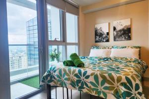 een slaapkamer met een bed en een groot raam bij BGC Uptown Park Suites w/balcony City View 100mbps in Manilla