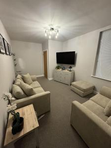 a living room with couches and a flat screen tv at Jasmine Cottage, Newbiggin by the sea in Woodhorn