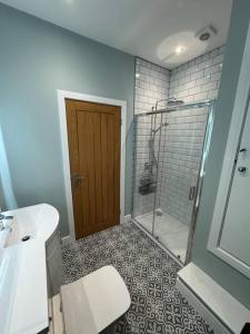 a bathroom with a shower and a toilet and a sink at Jasmine Cottage, Newbiggin by the sea in Woodhorn