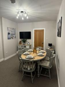 uma sala de jantar com uma mesa de madeira e cadeiras em Jasmine Cottage, Newbiggin by the sea em Woodhorn