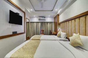 a hotel room with two beds and a flat screen tv at Hotel Flysky Rooms & Banquets in Navi Mumbai