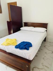 - un lit avec des draps blancs et des vêtements bleus dans l'établissement Enjoy Villa Weligama, à Weligama