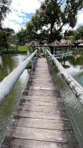 un ponte di legno su un corpo idrico con panche di Pousada Recanto dos Cisnes a Betim