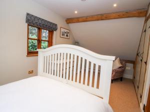 a white crib in a childs bedroom with a window at Pultheley Cottage in Montgomery