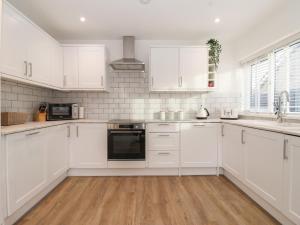 a white kitchen with white cabinets and a sink at The Coastal Hideaway in Hornsea