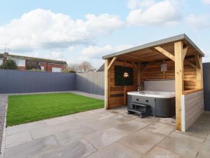 a garden with a hot tub and a wooden gazebo at The Coastal Hideaway in Hornsea