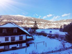 una casa cubierta de nieve con un campo y montañas en Hotel Gasthof Stranachwirt, en Sankt Michael im Lungau