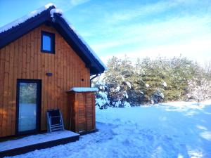 uma cabana de madeira com uma cadeira na neve em Ślusarnia-domek z sauną nad jeziorem, Kaszuby em Żuromino