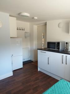 a kitchen with white cabinets and a microwave at Two Birds Weekly Stay in Malmesbury