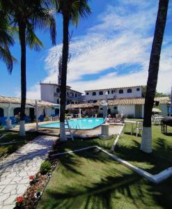 a resort with a swimming pool and palm trees at Pousada da Bia in Rio das Ostras