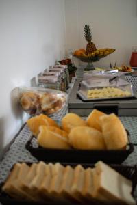 a buffet of food with bread and other foods at Pousada da Bia in Rio das Ostras