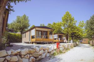 a yellow tiny house with a stone wall at Camping Piantelle in Moniga