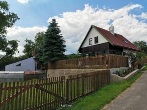 a house behind a wooden fence with a fence at Cozy cottage Geltschberg Nr. 1 in Liběšice
