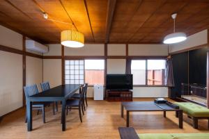 salon ze stołem, krzesłami i telewizorem w obiekcie Konpira Machiya USU w mieście Kotohira