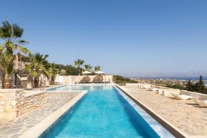 a pool at a resort with chairs and palm trees at Calme Boutique Hotel - Adults Only in Drios