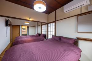 two beds in a room with purple sheets at Konpira Machiya USU in Kotohira