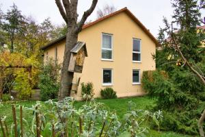 una casa gialla con un albero in cortile di My CozyPlace - Zimmer für Zwei a Dresda