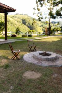 two chairs and a fire pit in a park at Chalés Recanto da Mantiqueira in Gonçalves